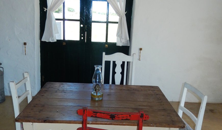 Vlei Cafe Cottage: Vlei Cafe Cottage - There is a dining are with four chairs overlooking the kitchenette that is equipped with a small gas fridge with a gas hob and crockery and cutlery.