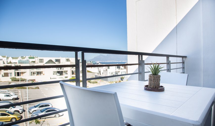 The apartment features a balcony furnished with a table and two chairs.