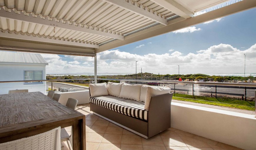 The to a covered balcony with seating, an 8-seater dining table and chairs, and a built-in braai in Struisbaai, Western Cape, South Africa