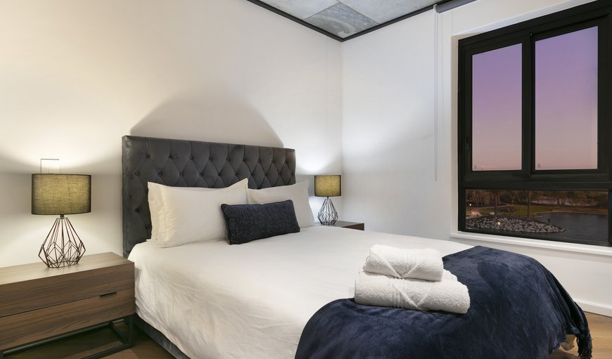 Executive Self-catering Apartment: The bedroom has a clean and modern aesthetic, featuring a queen bed