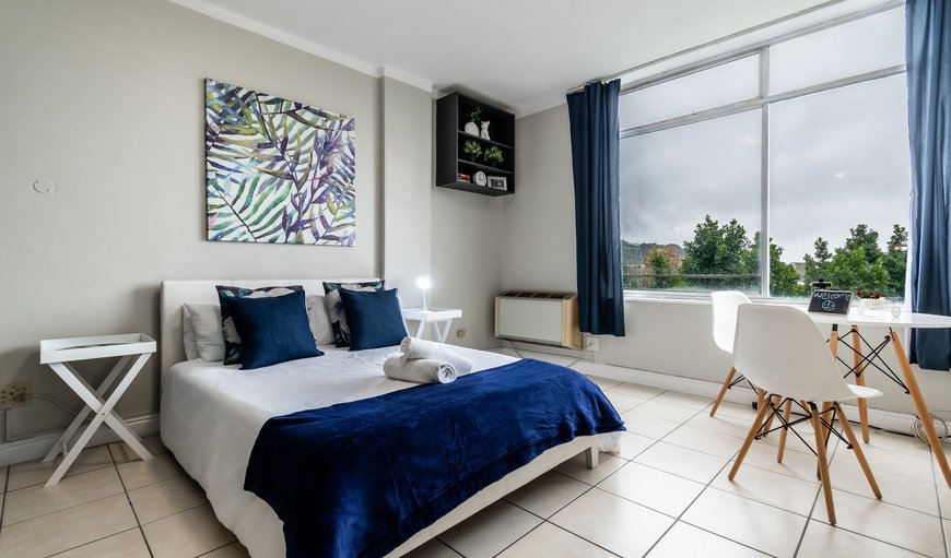 The layout of the studio apartment with the bedroom area (double bed), along with the dining table which can also be used as a dedicated workspace, all the while enjoying mountain and city views from the large slide-open aluminum windows. in Gardens, Cape Town, Western Cape, South Africa